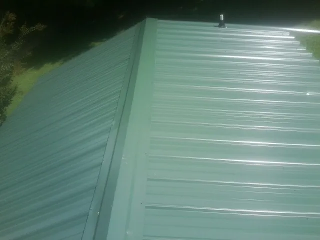 New green metal panels meeting at the ridge of a roof — Flat Roof Repair work by our crew in Flourtown
