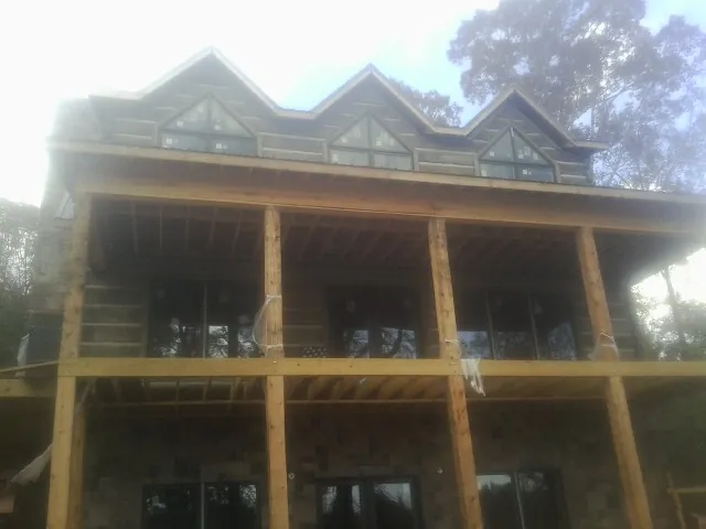 Dormers and porch framing on a large log home under construction — Roof Coating work by our crew in Flourtown