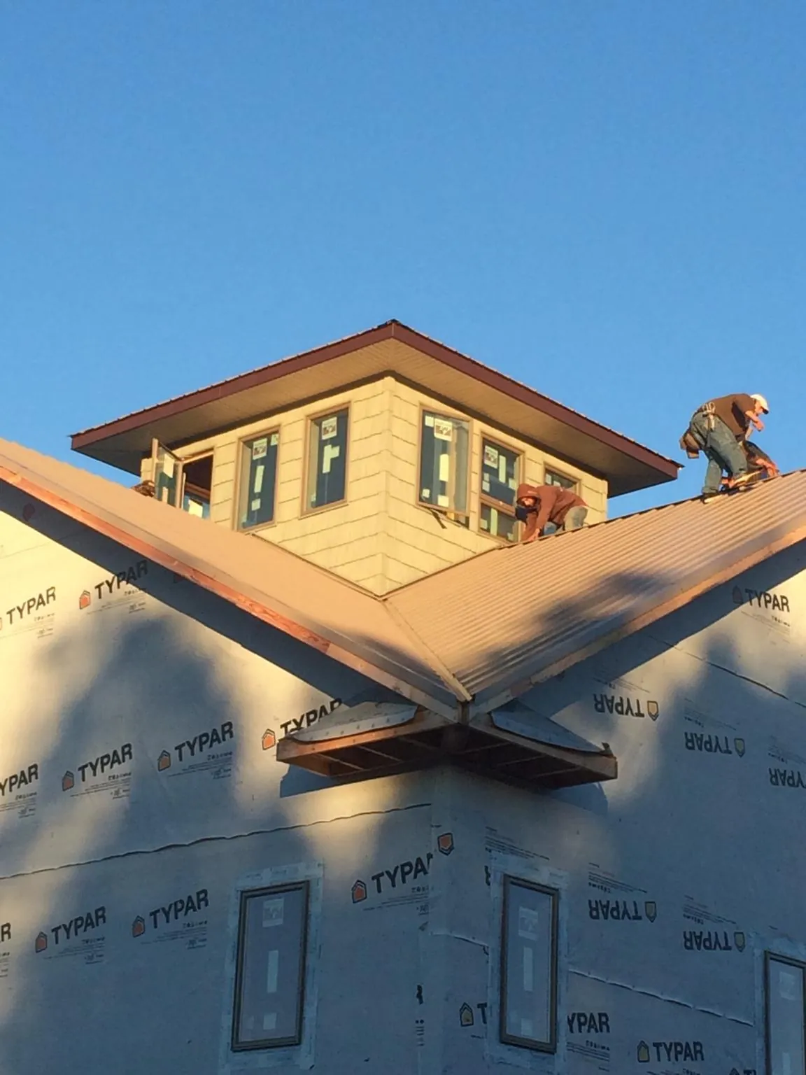 Roofers working around a rooftop cupola on a new metal roof at sunset — Roof Waterproofing in Flourtown by Roofing Brothers